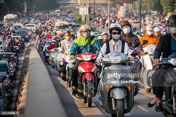 Motorbike drivers covered-up with face masks try to get through the morning peak hour traffic at Nga Tu So intersection on November 4, 2016 in Hanoi,...