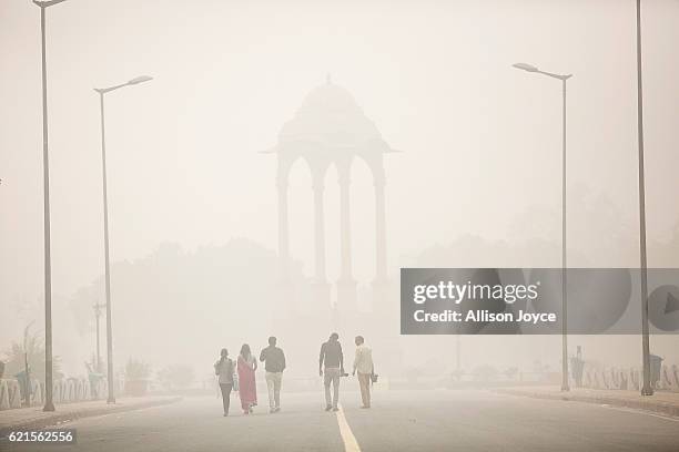 People walk near India gate amid heavy dust and smog November 7, 2016 in Delhi, India. People in India's capital city are struggling with heavily...