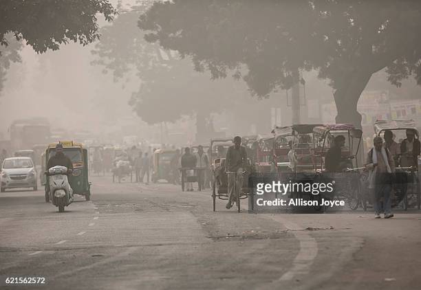 Traffic moves along a street amid heavy dust and smog November 7, 2016 in Delhi, India. People in India's capital city are struggling with heavily...