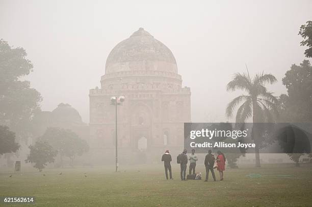 People stand in a park amid heavy dust and smog November 7, 2016 in Delhi, India. People in India's capital city are struggling with heavily polluted...