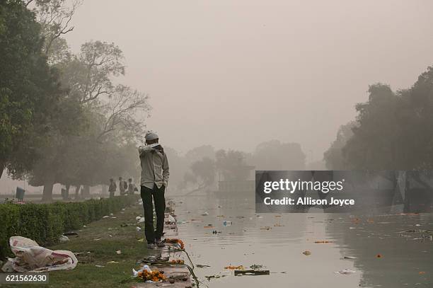 Man walks near a park littered with trash from a festival amid heavy dust and smog November 7, 2016 in Delhi, India. People in India's capital city...