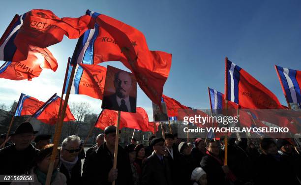 Kyrgyz communist party supporters holding red flags gather in front of a monument to the first Soviet leader Vladimir Lenin during a rally to mark...