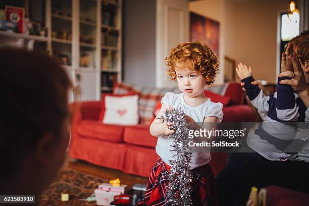 niña ayudando a su madre con las decoraciones navideñas - espumillón fotografías e imágenes de stock