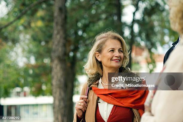 mature women. - two elderly friends chatting in a community park stock pictures, royalty-free photos & images