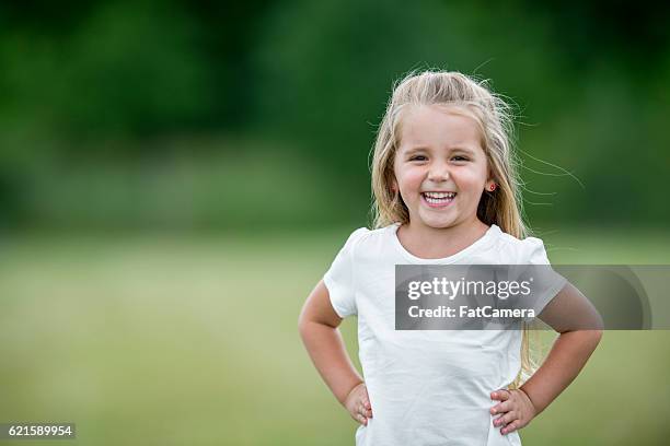 kleines mädchen steht draußen im park - blonde girl smiling stock-fotos und bilder