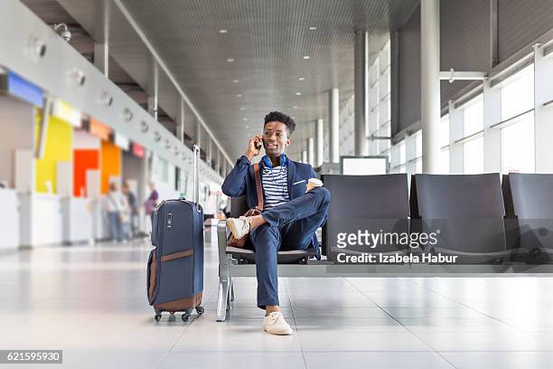 young man talking on phone at airport lounge - airport stock pictures, royalty-free photos & images