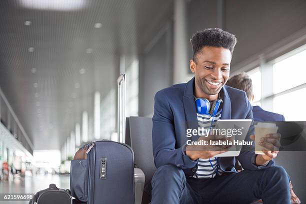 young african using digital tablet airport lounge - e reader stock pictures, royalty-free photos & images
