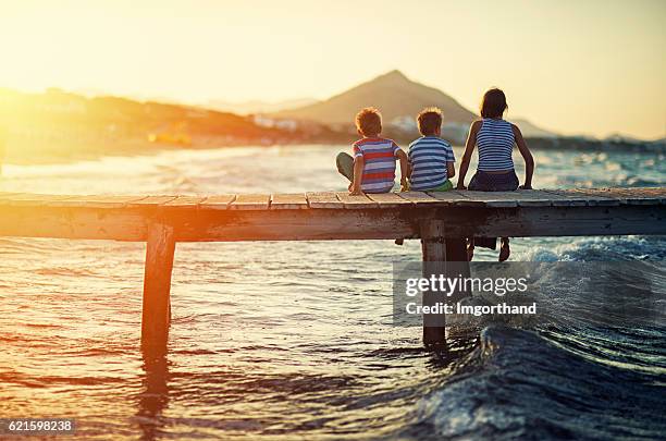 vacaciones de verano - niños sentados en el muelle del mar - islas baleares fotografías e imágenes de stock