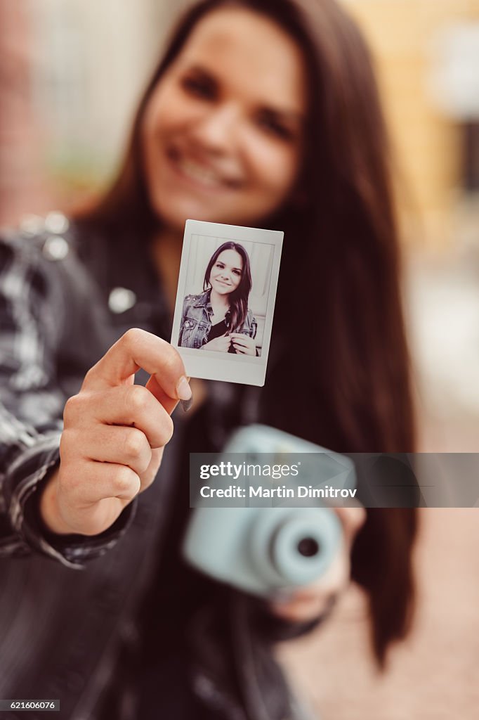 Teenage girl showing instant photo