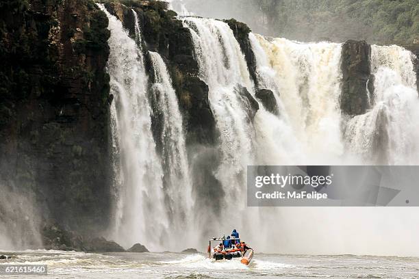 little boat aproaching iguazu falls - iguazu falls boat stock pictures, royalty-free photos & images