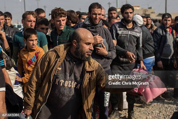 Man shows his ID card to Iraqi special forces soldiers at a civilian screening check point after fleeing fighting in Mosul on November 7, 2016 in...