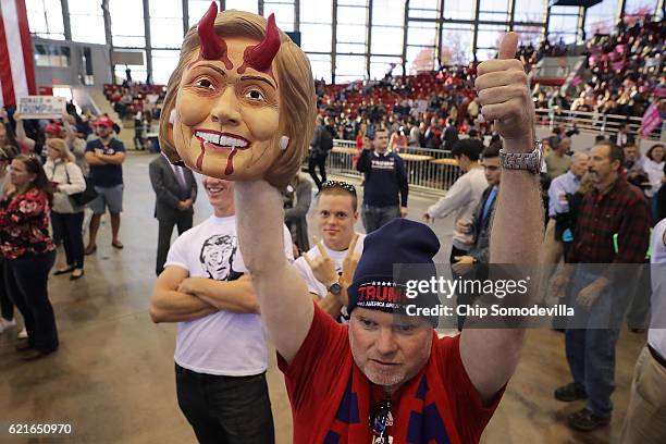 Man holds a mask of Democratic presidential nominee Hillary Clinton with devil horns and bloody teeth during a campaign rally with Republican...