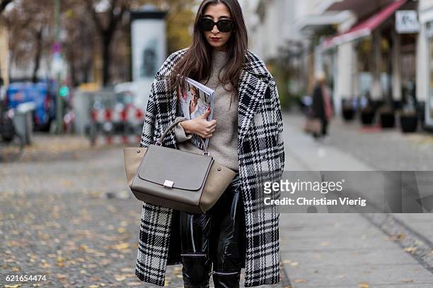Nadja Ali holding a German Vogue magazine wearing a white black checked Zara coat, a creme Zara jumper, black Zara leather pants, Celine bag on...