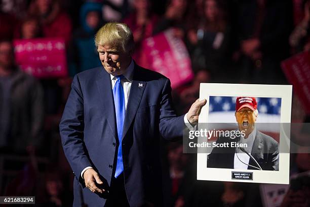 Republican presidential candidate Donald Trump holds up a picture of himself that supporter handed him at the end of his rally at the SNHU Arena on...