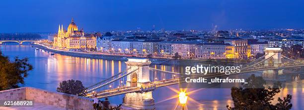 panoramic of chain bridge and parliament in budapest at dusk - budapest stock pictures, royalty-free photos & images