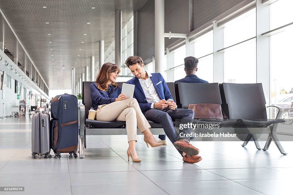 Business couple waiting for flight at airport lounge