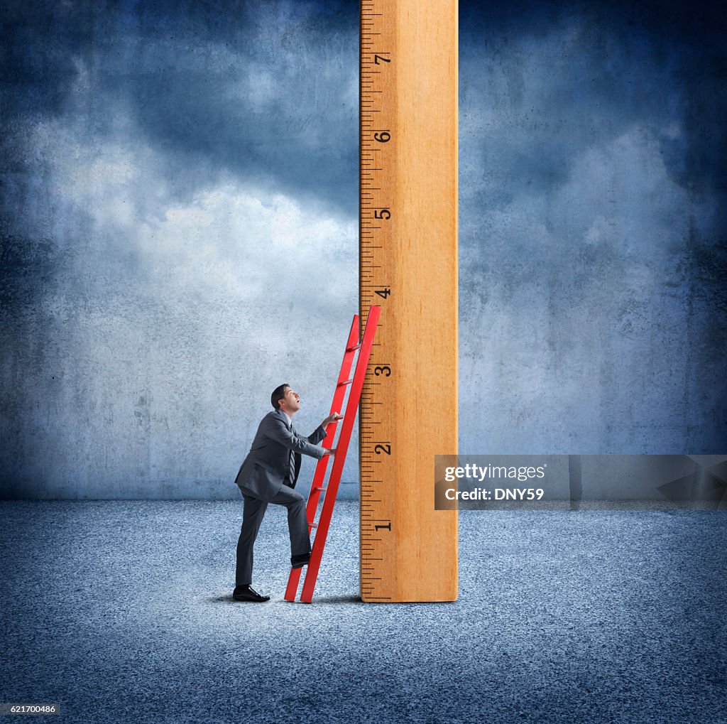 Businessman Uses Ladder To Climb Wooden Ruler