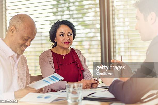 insurance agent talking to older couple of african ethnicity - investment brochures stockfoto's en -beelden