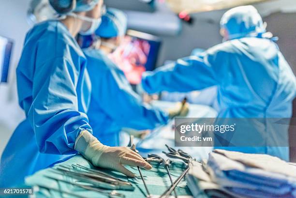 surgeons in full surgical gear during operation - operationssal bildbanksfoton och bilder