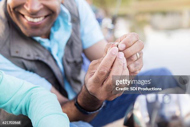 cheerful grandfather teaches his granddaughter to bait a hook - vishaak visgerei stockfoto's en -beelden