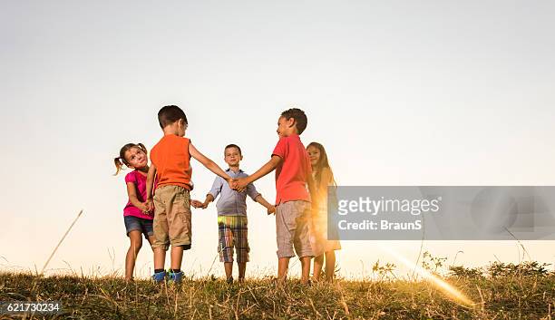 below view of cute friends playing ring-around-the-rosy at sunset. - ring around the rosy stock pictures, royalty-free photos & images