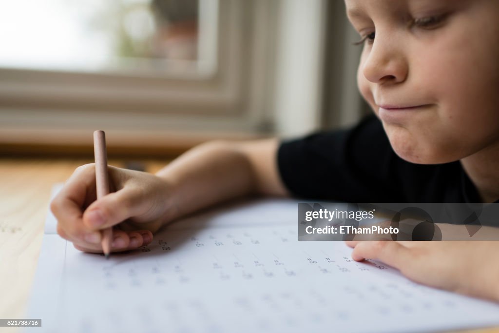 Schoolboy at his desk doing his maths homework