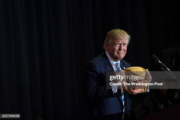 Republican presidential candidate Donald Trump holds up a mask depicting himself as he speaks during a campaign event at Robarts Arena at the...
