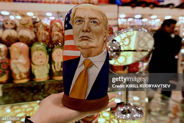 Woman examines a traditional Russian wooden nesting doll, a Matryoshka doll, depicting US Republican presidential nominee Donald Trump at a gift shop...