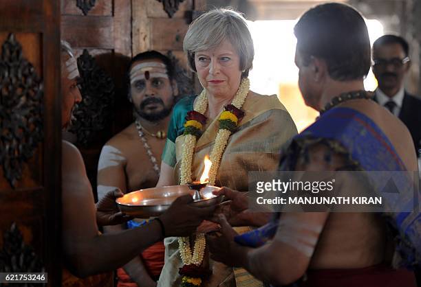 Britain's Prime Minister Theresa May stands amidst Hindu priests after offering prayers to the Hindu deity Lord Shiva during a visit to Someshwara...