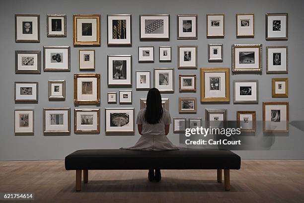 Member of staff poses infront of photographs belonging to Elton John during a press preview for "The Radical Eye: Modernist Photography from The Sir...