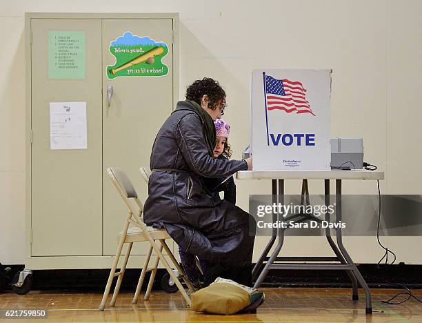 Willa Domina watches her mother, Emily Katz, votes at a polling station on November 8, 2016 in Durham, North Carolina. Schools serving as voting...