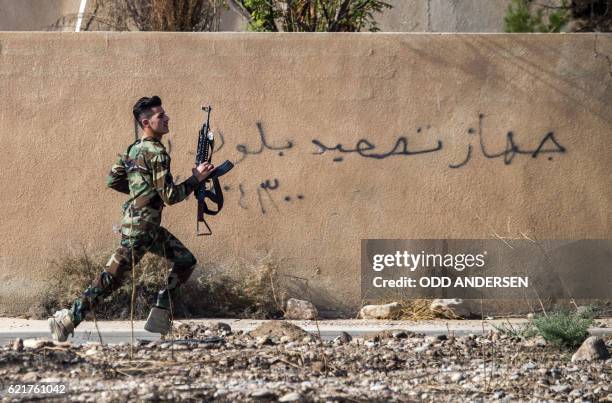 Peshmerga fighter runs to take position as the Iraqi Kurdish forces pushed deeper into the town of Bashiqa during street battles against Islamic...