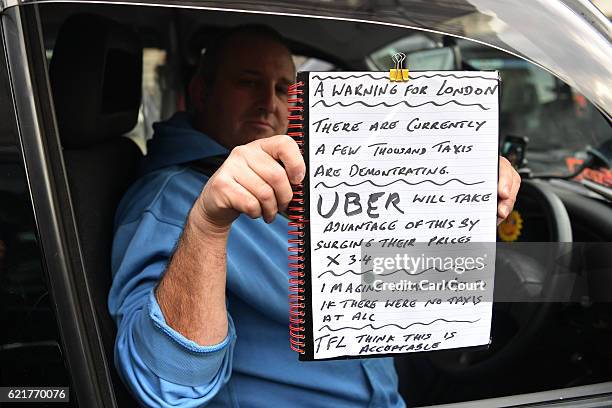 Black cab driver holds a poster as he takes part in a protest to highlight congestion and air pollution on November 8, 2016 in London, England....