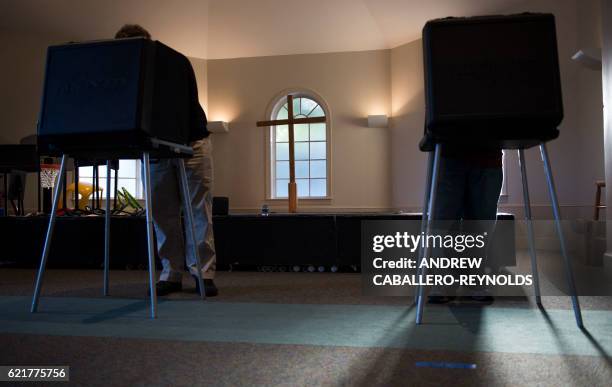 People vote in a polling place at a church in Fairfax, Virginia during the US presidential election on November 8, 2016.