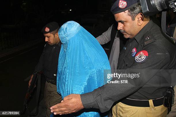 Pakistani policemen escort Afghan refugee woman Sharbat Gula as she leaves the Lady Reading Hospital where she was treated, in Peshawar on November 9...