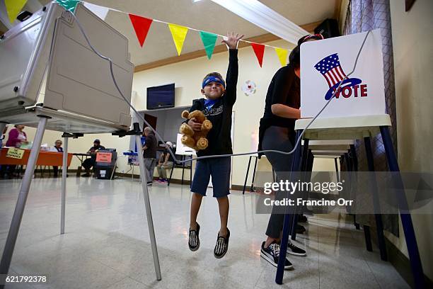 Damaris Marti right, of East Los Angeles votes as her son wearing a super hero mask Matthew Jasinsky left, jumps next to her at the polling location...