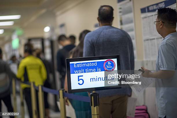 Sign showing a wait time is displayed as voters stand in line to cast their ballot at the San Francisco City Hall polling location in San Francisco,...