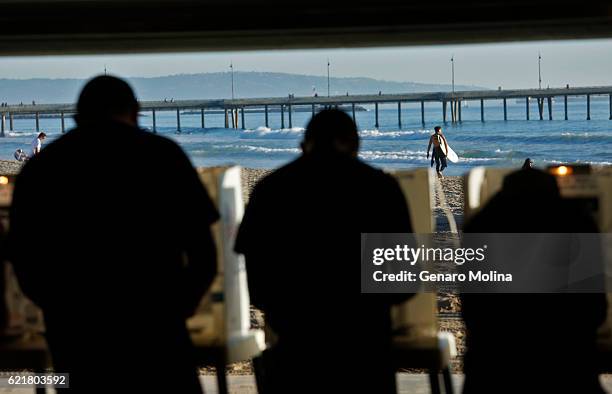 People cast their votes as a surfer heads to the water against a backdrop of the Venice Pier at the Los Angeles County Fire Department Lifeguard...