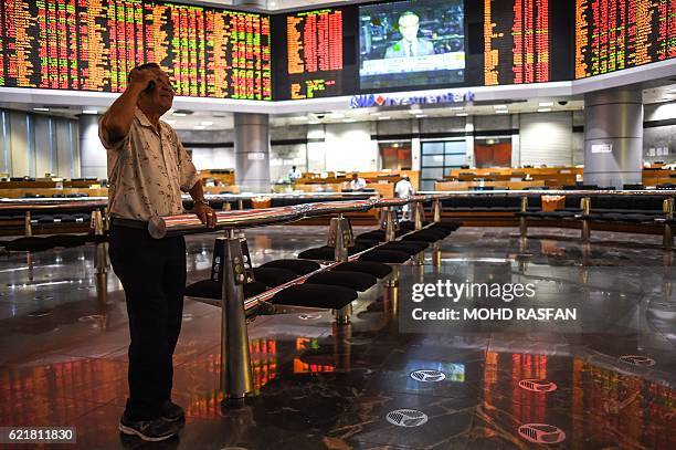 Trader talks to his mobile phone before electronic boards showing stock movements during the final day of the US presidential election at a private...