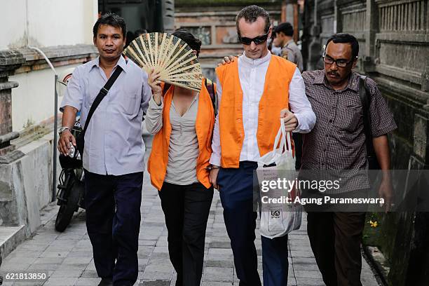 Australian Sarah Connor who covers her face with fans and British David taylor walk as they arrive at Denpasar Court for their first trial on...