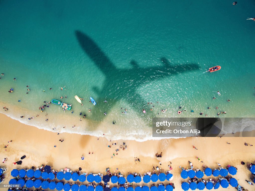 L’ombre de l’avion sur une plage bondée