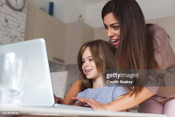 cute girl and mother using laptop at home - parental control stock pictures, royalty-free photos & images