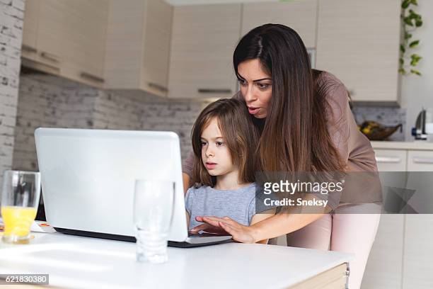 cute girl and mother using laptop at home - parental control stock pictures, royalty-free photos & images