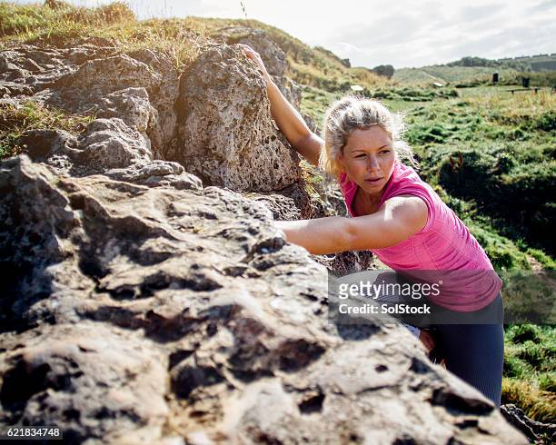 mujer subiendo por una cara de roca - escalada libre fotografías e imágenes de stock