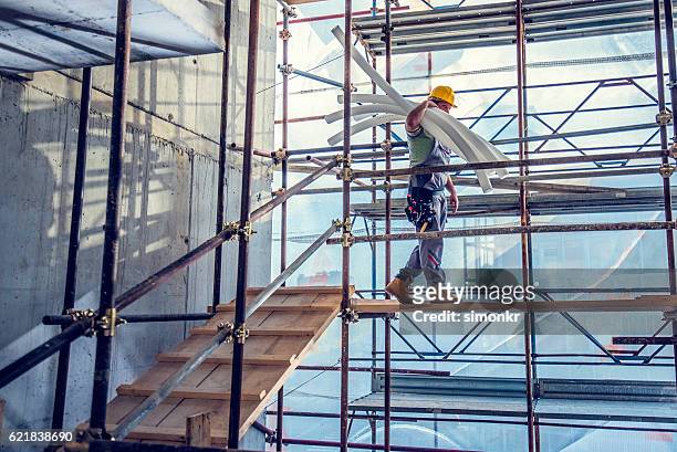 worker carrying pipes - scaffolding stock pictures, royalty-free photos & images