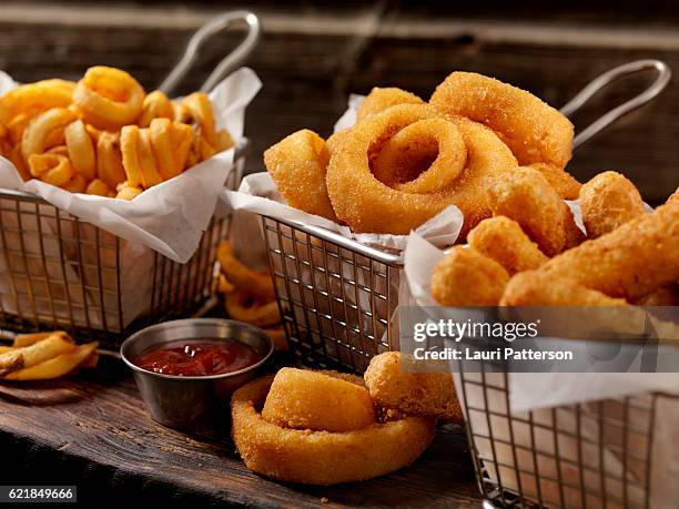 baskets of onion rings, curly fries and cheese sticks - gefrituurd stockfoto's en -beelden