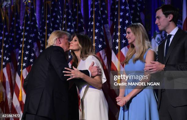 Republican presidential elect Donald Trump kisses his wife Melania as his daughter Ivanka looks on during election night at the New York Hilton...