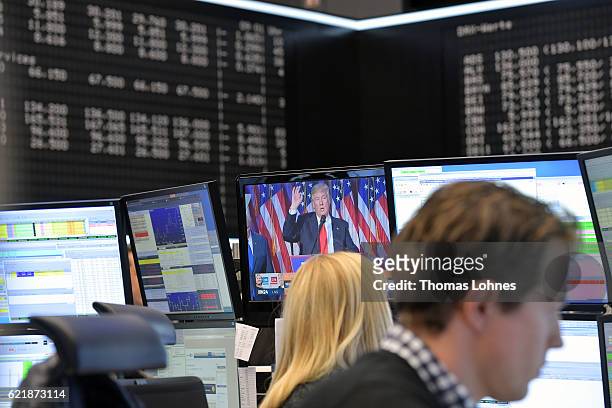 Trader works at the Frankfurt Stock Exchange while Donald Trump is seen on a monitor in the background on November 9, 2016 in Frankfurt, Germany....