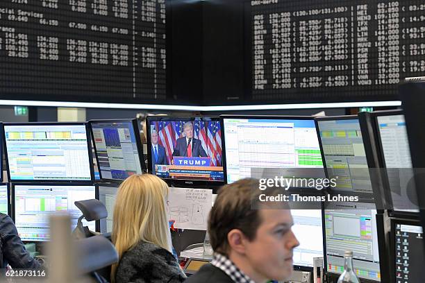 Trader works at the Frankfurt Stock Exchange while Donald Trump is seen on a monitor in the background on November 9, 2016 in Frankfurt, Germany....