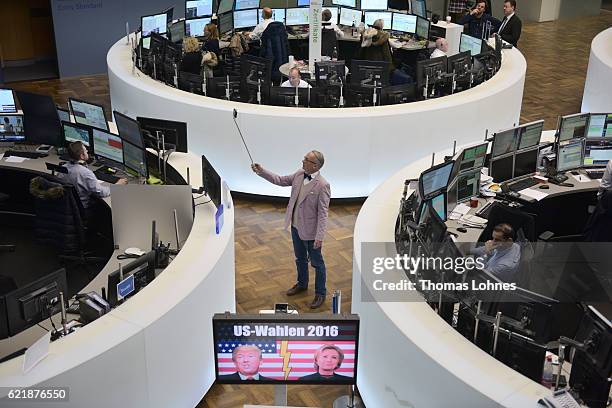 Journalist takes a picture of the graph showing the day's course of the DAX index at the Frankfurt Stock Exchange while a TV monitor with the...